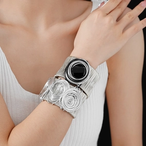 Detail of layered silver wire wrapped cuffs with large black resin accent on model