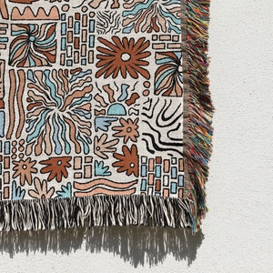 Detailed view of bohemian woven blanket with abstract floral texture and multi-color tassels