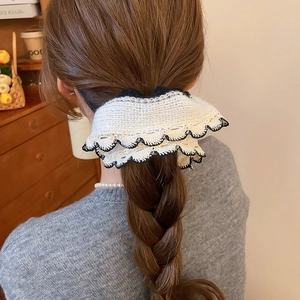 White knitted lace scrunchie with black crochet edge worn on a low ponytail hair