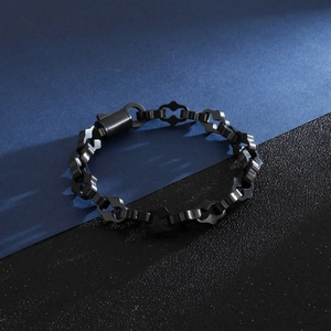 Détail d'un bracelet gourmette en acier inoxydable noir avec motifs ajourés sur les maillons