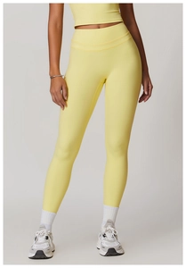 Detail showing the light yellow high-waisted yoga leggings and tight cropped sports top
