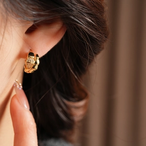 Close-up of 14K gold plated serpent earrings with zircon on a model's ear