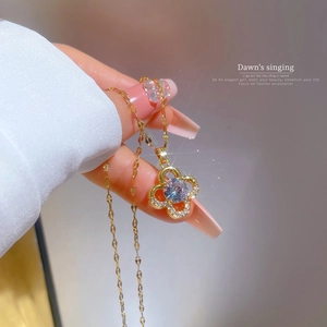 Detail of a gold clover necklace with zircon pave setting held in hand under warm light