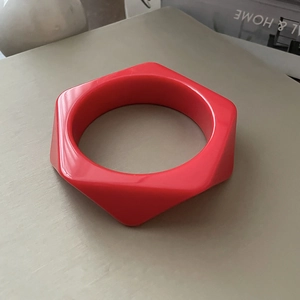 Detail of red hexagonal resin bangle showing wide geometric design and glossy finish