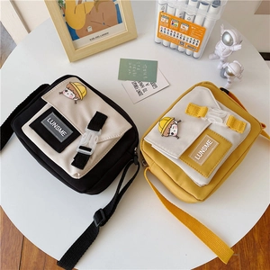 Close-up of canvas crossbody bags with buckle strap and cute cartoon girl patch detail
