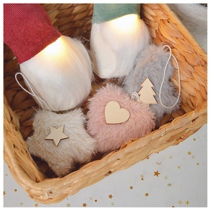 Close-up of plush Christmas ornaments with LED gnomes, hearts, and stars in a woven basket