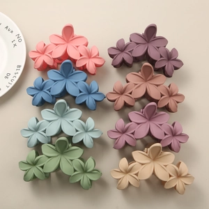 Detail showing eight colors of matte frosted flower hair claws arranged in two rows