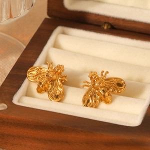 Elegant 18K gold-plated stainless steel bee stud earrings on a vintage wooden box