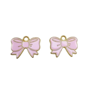 Close-up of two pink enamel bow charms with golden metal edges for DIY jewelry making