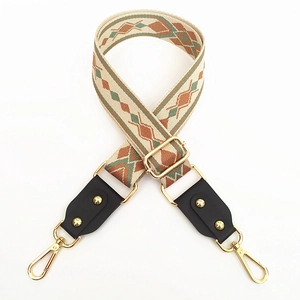 Detail of adjustable woven canvas strap with green geometric patterns and gold metal hooks