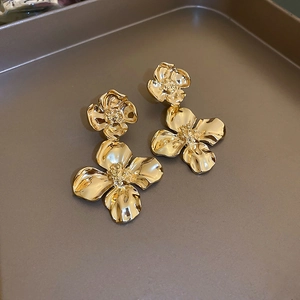 Detailed macro view of golden flower earrings with artistic wrinkled metal texture