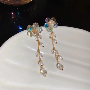 Macro shot of long crystal flower tassel earrings with pearls on a seashell tray