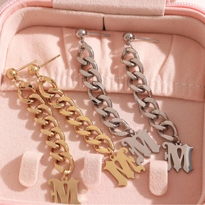 Boucles d'oreilles lettre M en or et argent avec chaîne gourmette dans un écrin