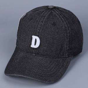 Detail shot of white letter D embroidery on black washed denim baseball cap