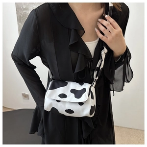 Detail shot of a small cow-print crossbody bag with stylish butterfly knot strap