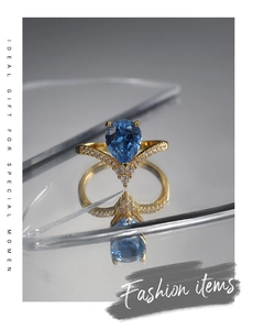 Close-up of a pear-cut blue zircon ring with a V-shaped diamond-set gold band