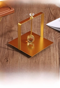 Detail of gold metal tissue holder with crystal ball handle on a dark wood surface