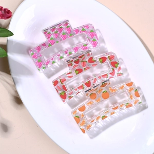 Pinces à cheveux aux motifs de fruits et fraises sur un plateau de présentation blanc