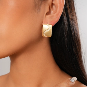 Detailed view of 18K gold plated rectangular earrings with S-shaped zircon wave on model