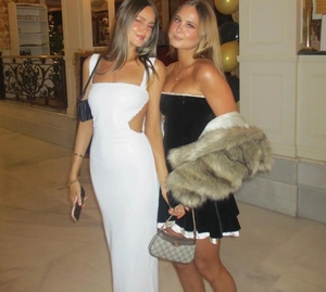 Detail of white side-cutout halter maxi dress and black mini dress with fur shawl