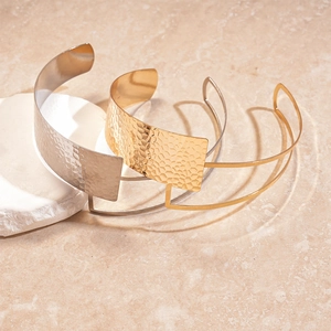 Golden and silver metal bangles with hammered texture on a marble background