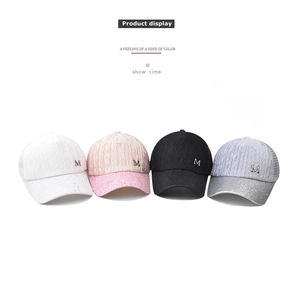 Close-up of four glitter baseball caps in white, pink, black, and purple with M logo