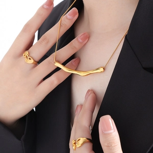 Parure collier géométrique doré et bagues mains enlacées sur veste noire