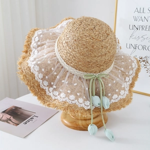 Detail of raffia hat featuring white lace, polka dot mesh, and tulip ribbon pendant