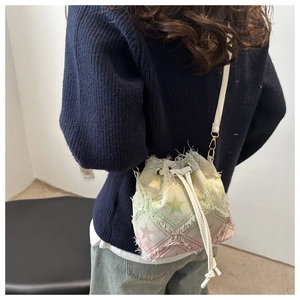Detail of denim cloud bag showing star pattern print and frayed fringe tassel edges