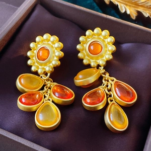 Gros plan de boucles d'oreilles tournesol vintage avec pierres ambrées sur satin brun