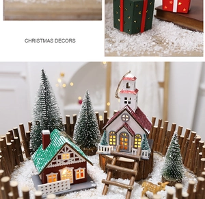 Close-up of lighted Christmas wooden house with mini deer and snow-covered pines