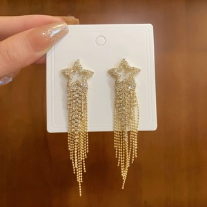 Detail of star-shaped tassel earrings with golden chain fringe and sparkling rhinestones