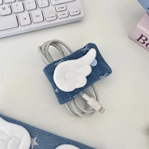 Blue denim cable organizer with plush wings holding a white charging cord on a desk