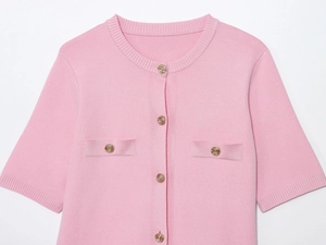 Dettaglio del cardigan in maglia rosa con trama fine e bottoni dorati a rilievo