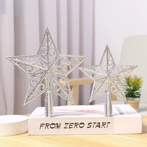 Silver hollow out metal star Christmas tree toppers in two sizes on a white book