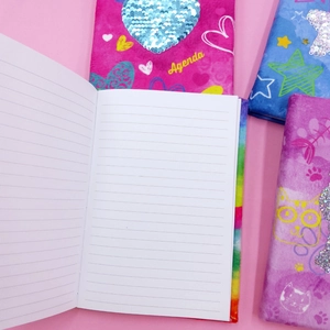 Detail view of colorful sequin notebooks with lined pages and cartoon patterns