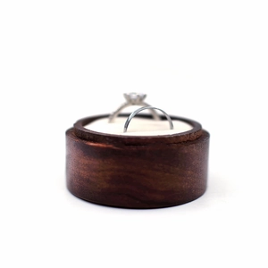 Macro shot of a wooden round engagement ring box with two silver wedding rings