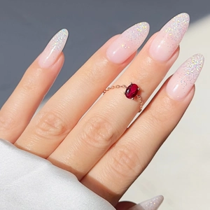 Close-up of a gold chain ring featuring an oval red zircon stone on silk fabric