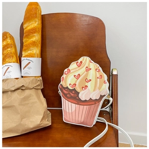 Detail of cupcake-shaped crossbody bag with heart prints on a vintage wooden chair