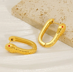 Détail de boucles d'oreilles serpent dorées avec design en U et textures d'écailles