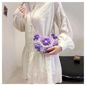 Detailed view of handmade crochet crossbody bag with purple 3D puff flowers worn by a model