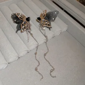 Silver butterfly tassel earrings with black heart crystal and metallic fringe details