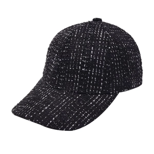 Detailed close-up of a stylish black and white tweed baseball cap showing woven texture