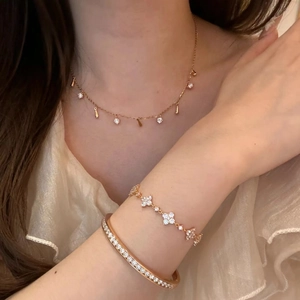Close-up of rose gold jewelry set featuring clover bracelet and diamond bangle