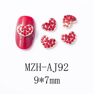 Vue macro des bijoux d'ongles cœur 9x7mm avec cadre doré et strass rouges brillants