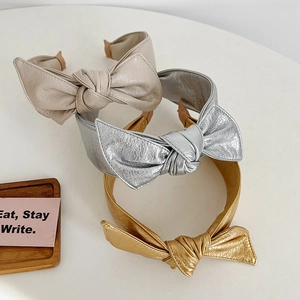 Three-piece faux leather bow headband set in cream, metallic gold, and silver finishes