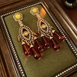 Detail shot of vintage flower earrings with tassels and brown beads on green velvet