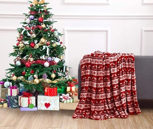 Detail of red Christmas flannel blanket with reindeer and snowflake patterns on a sofa