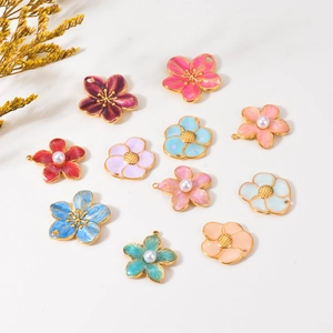 Macro detail of colorful enamel flower charms with pearls and gold metal loops for DIY jewelry