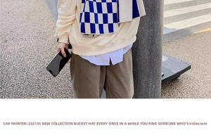 Blue and white checkerboard knit scarf styled with beige hoodie and striped shirt